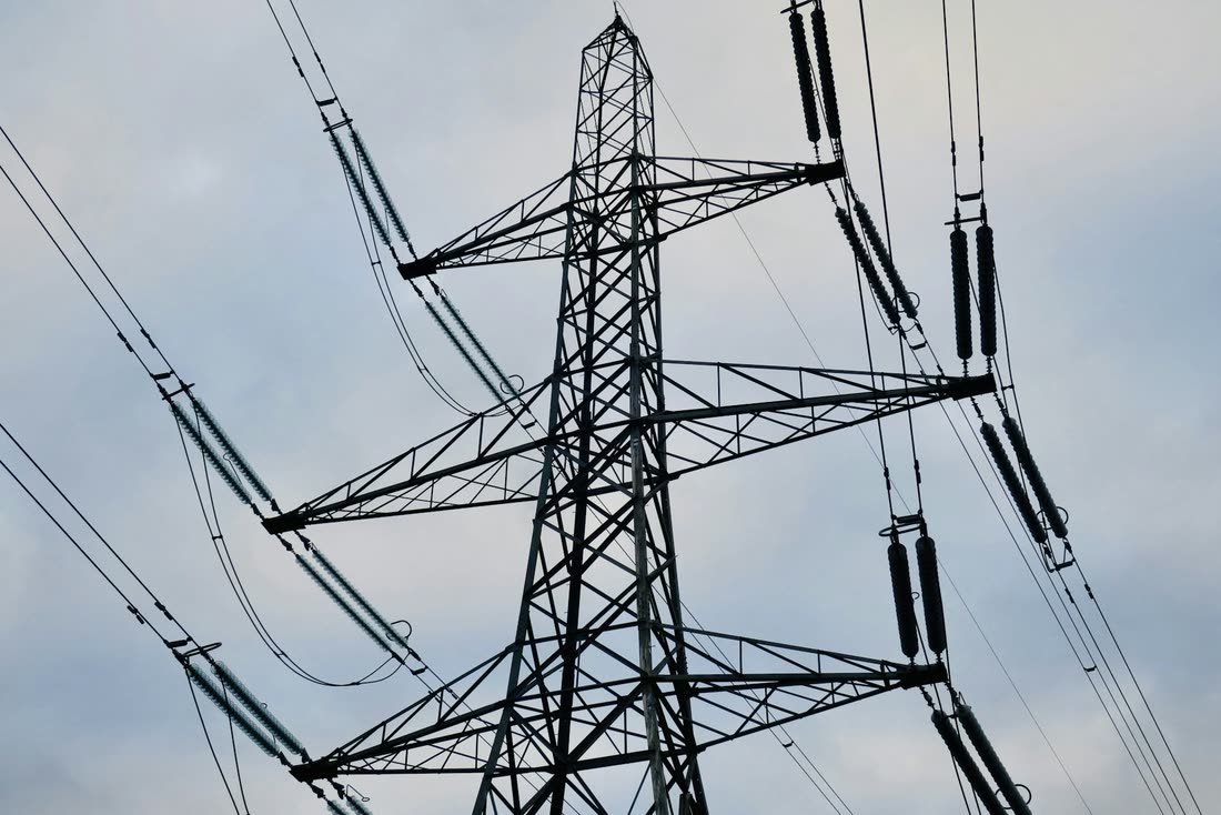 Looking up at a high-voltage pylon and its lines against a cloudy sky